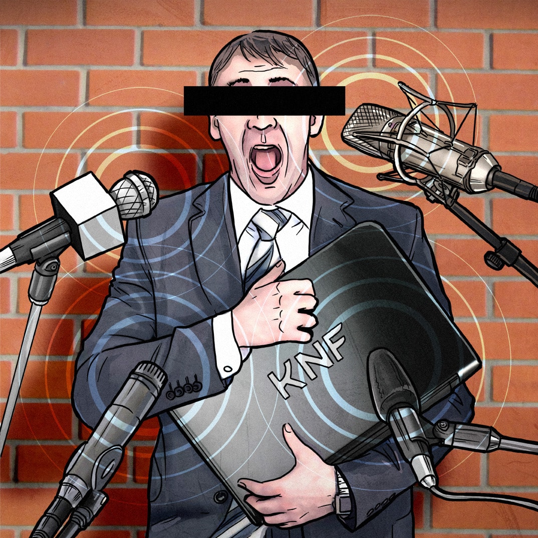 Prelegent w czarnym garniturze z teczką i z wymazanymi oczami stoi przed mikrofonami.