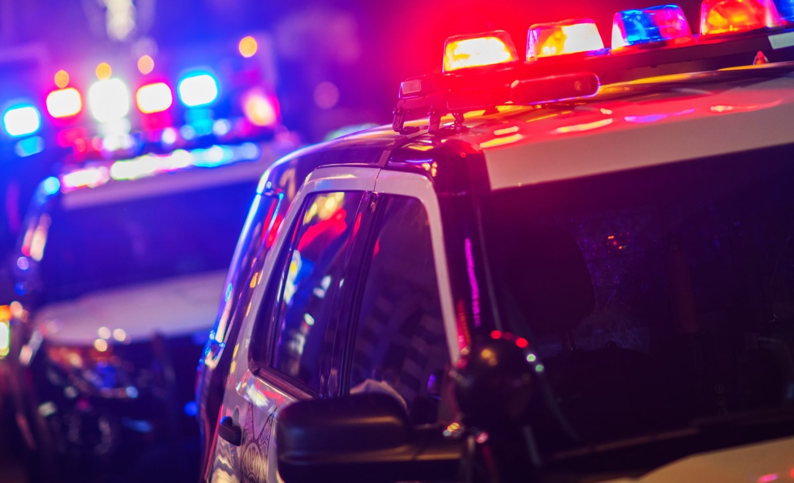 Fragment radiowozu policji z włączonym czerwono-niebieskim sygnałem