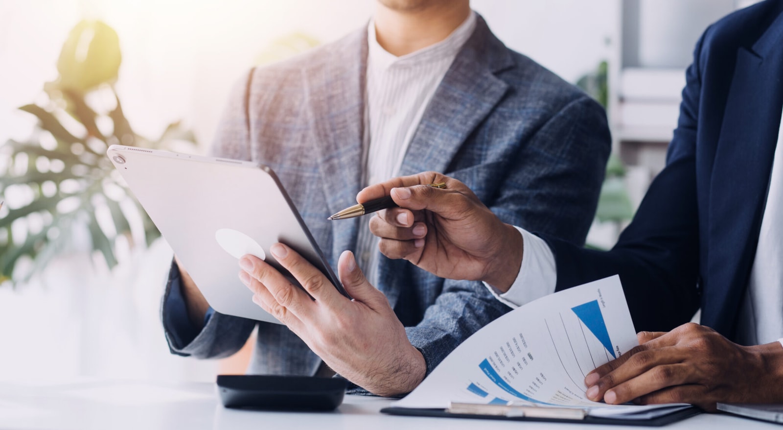 Financial analysts analyze business financial reports on a digital tablet planning investment project during a discussion at a meeting of corporate showing the results of their successful teamwork.
