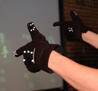 Te dziwaczne rękawiczki pozwalają przekazać komputerowi, czego od niego chcemy. Nie ma w nich żadnej elektroniki, kluczem są białe punkty, które wychwytuje kamera.