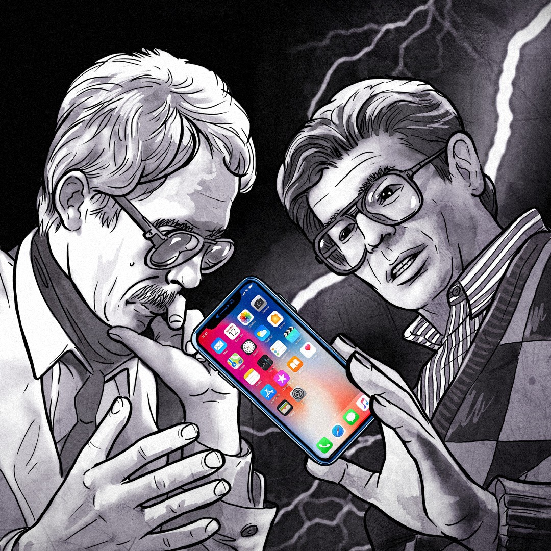 Andrzej Kurek i Zdzisław Kamiński przyglądają się smartfonowi.