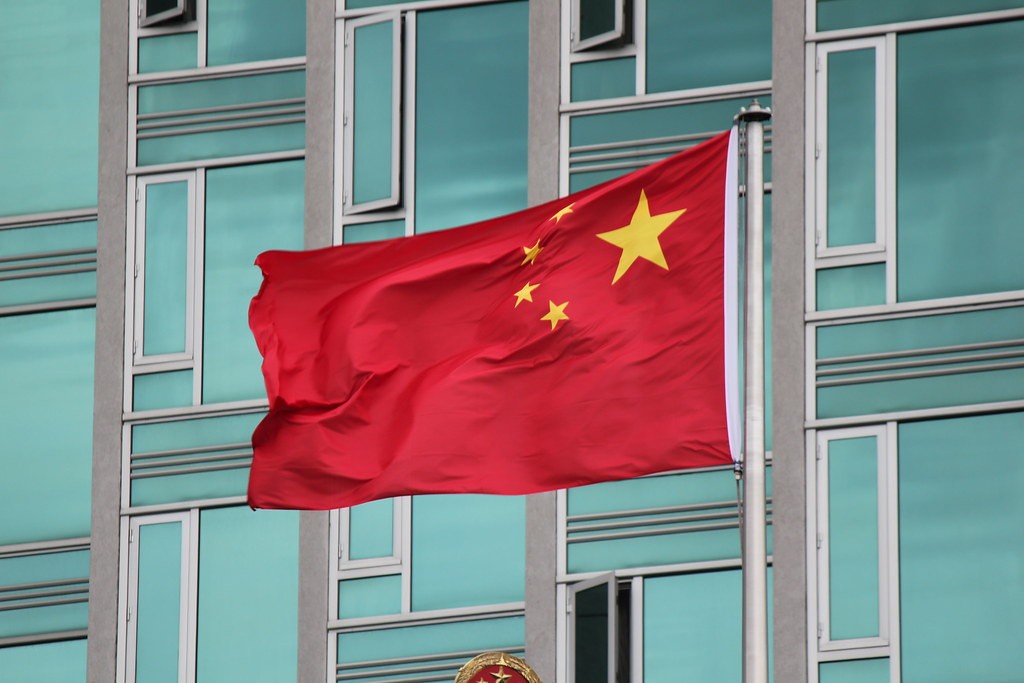 Chińska flaga na maszcie przed błękitnym budynkiem