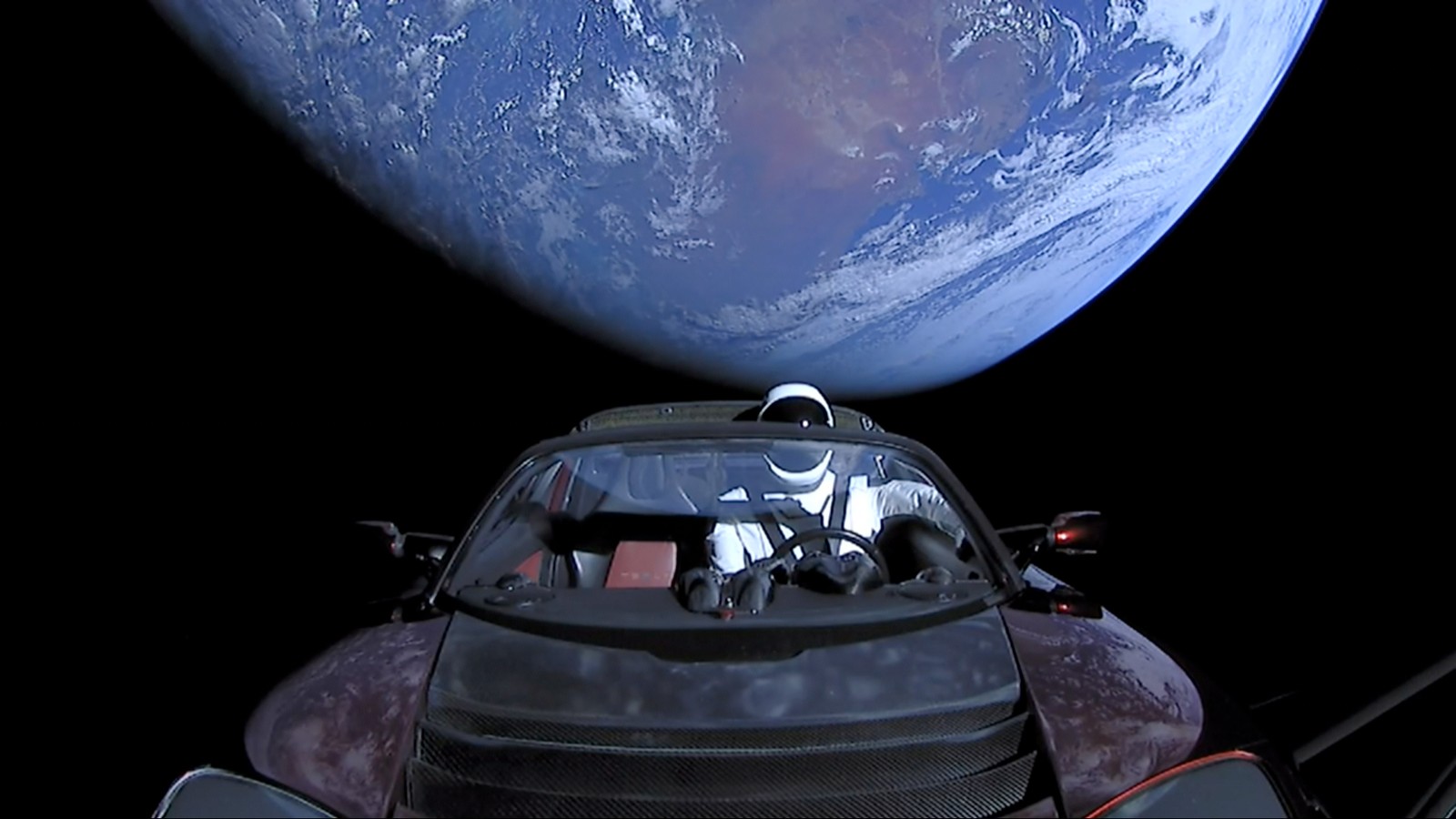 Tesla Roadster, a w nim manekin Spaceman z Ziemią w tle
