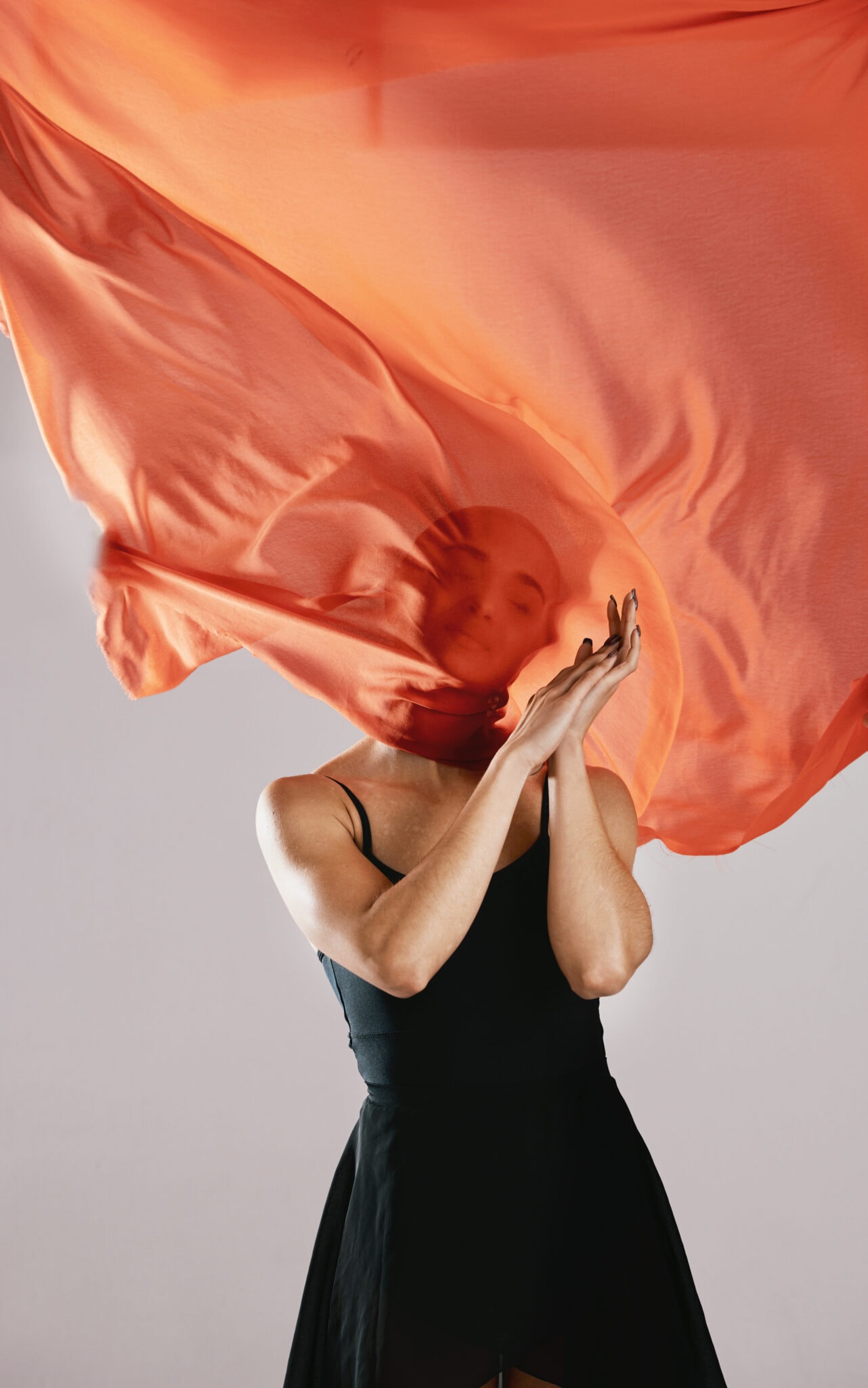 Fashion, fabric and breeze with a model in studio on a gray background for runway or magazine cover style. Abstract, textile wind and hidden face with a trendy young woman posing in a material outfit.
