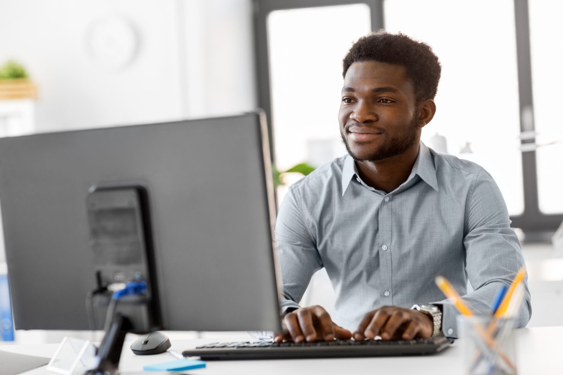business, people and technology concept – african american businessman with computer working at office